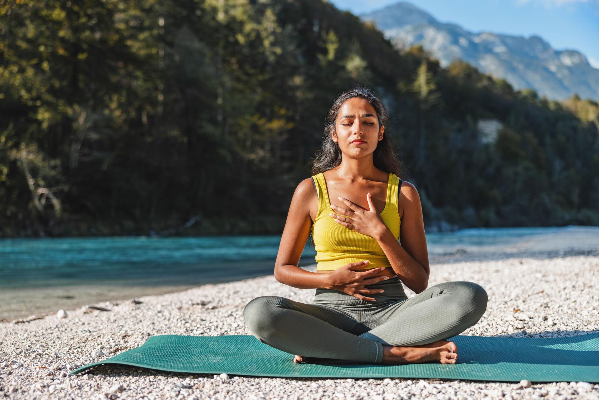 Young Woman Practicing Yoga Outdoors by River